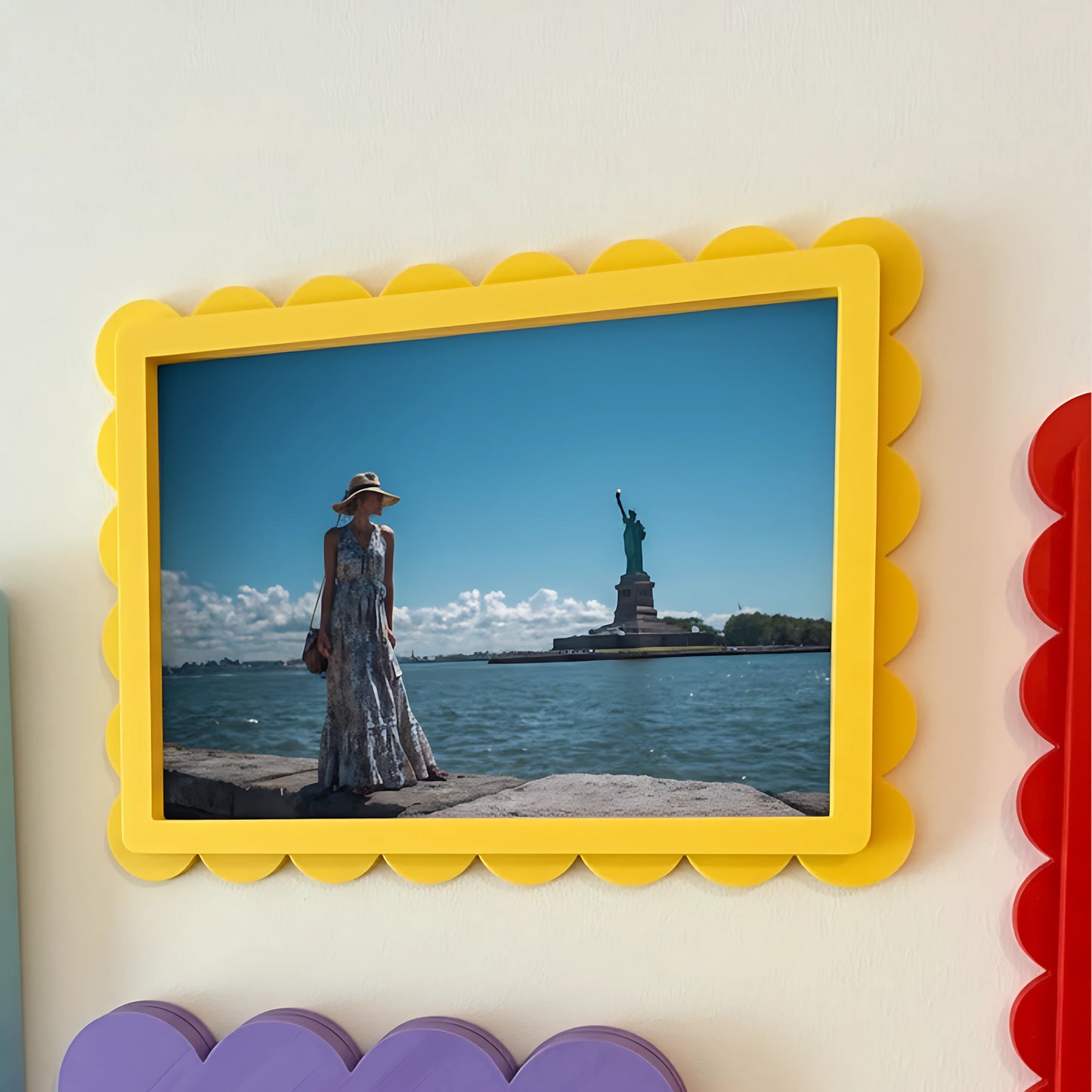 Woman in a dress and hat standing on a pier with the Statue of Liberty in the background, framed by a yellow scalloped border.