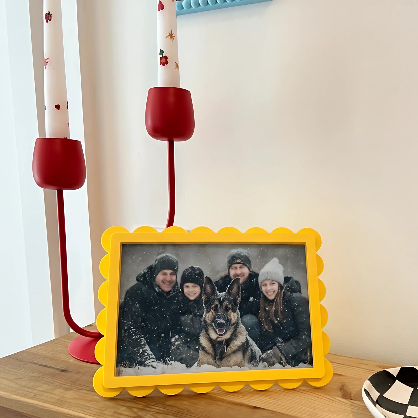 Yellow photo frame with a family and dog picture on a wooden surface.