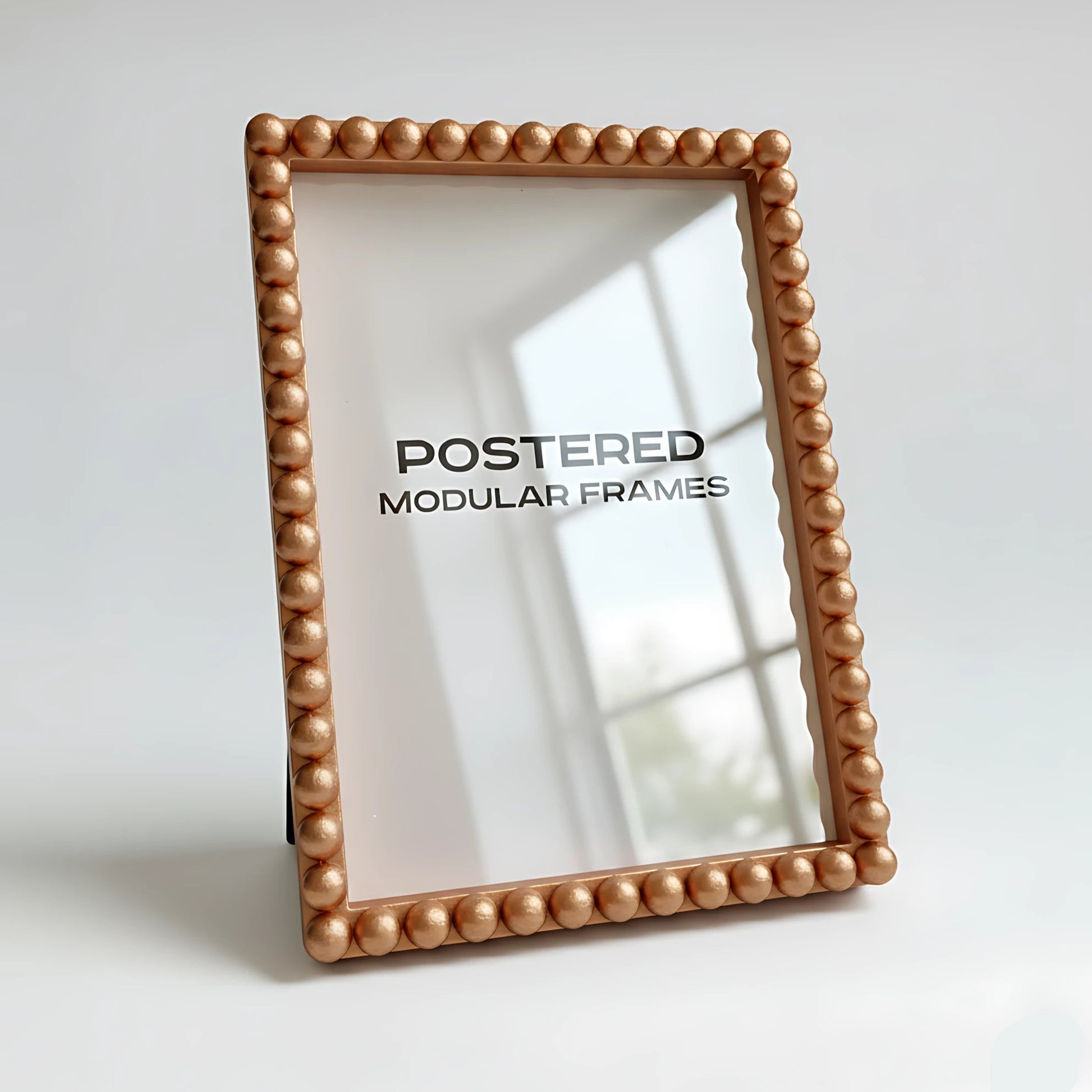 Gold beaded photo frame with 'POSTERED MODULAR FRAMES' branding on a light background