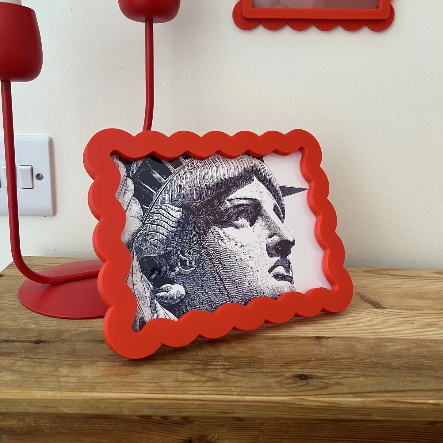 Small framed picture of a face on a wooden surface with a red lamp and 'London England' sign in the background.