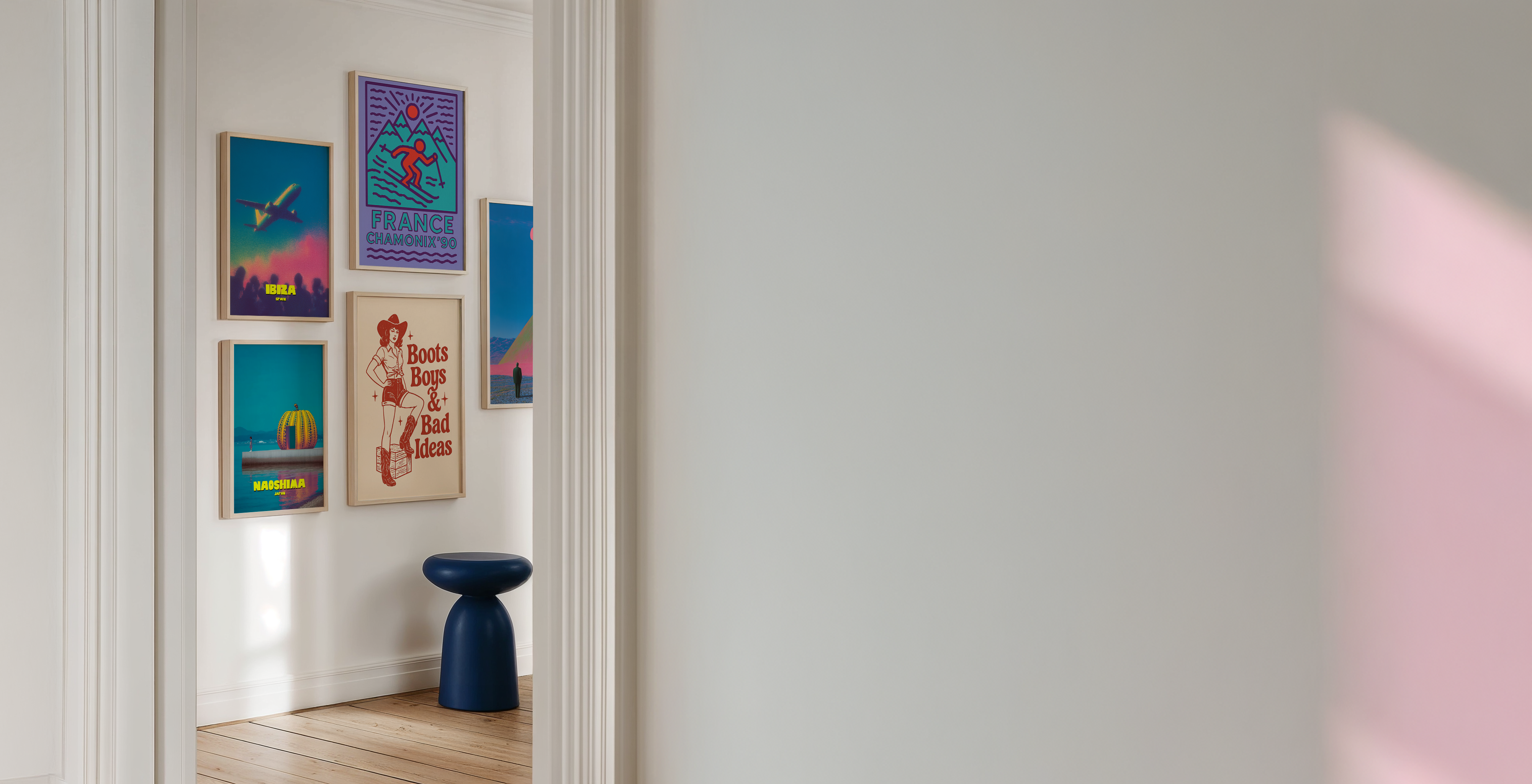 Colorful posters on a wall with a blue vase on a shelf.
